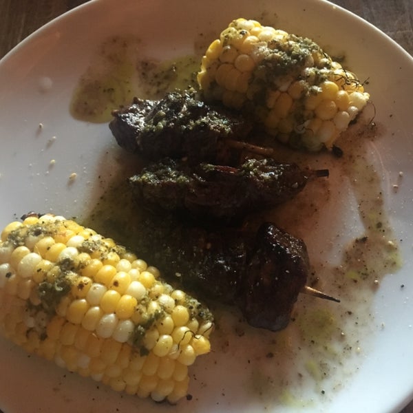 Steak bites alongside grilled corn and chimichurri sauce
