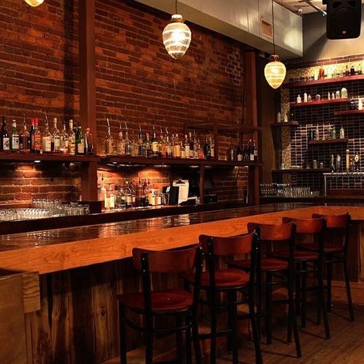 A simple wooden bar plays host to a full bar program complete with moonshine and boutique distilled spirits, making you wish smoking jackets were still in style.
