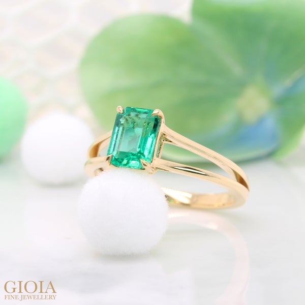 Emerald Engagement Ring Featuring a vivid green minor oil emerald crafted in polished yellow gold. Designed with timeless solitaire split shank cathedral that unite at mid band.