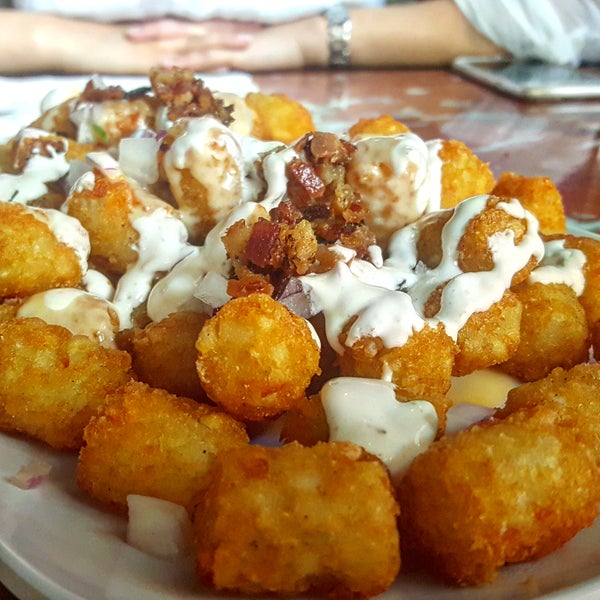 Getting loaded on beers? Then the Loaded Tots topped with cheddar cheese sauce, bacon, cilantro, red onion, & lime crema are a must!