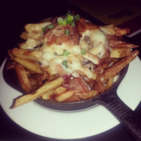 Their Poutine comes with hand-cut fries in a skillet, smothered in homemade gravy, cheese sauce, bacon bits, and scallions.