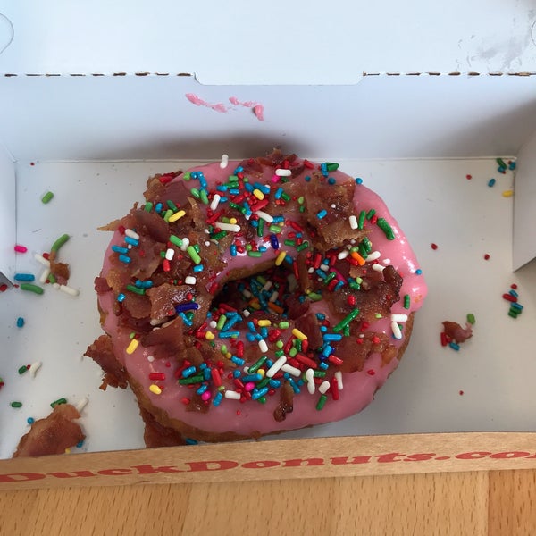 Donut with strawberry topping, sprinkles, and bacon.
