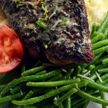The blackened red snapper is coated in savory blackening spices, sautéed in rendered duck fat and then served with green beans, jasmine rice and finished with Meuniere sauce.