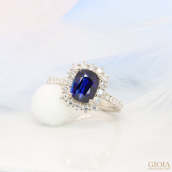 Blue Sapphire Halo Diamond Ring Featuring a royal blue sapphire with exceptional vivid saturation, surrounded by a halo of round brilliant diamonds.