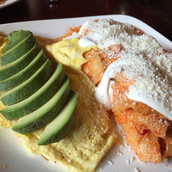 chilaquiles with very spicy salsa roja, cotija cheese, and sour cream with sliced avocado and scrambled eggs