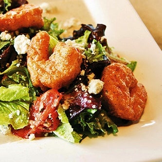 This salad has shrimp dipped in a spicy pimento batter then fried to perfection. A generous mix of greens & impossibly juicy marinated tomatoes dressed in their bacon blue cheese vinagrette, yum!