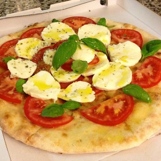 En lækker pizza Caprese 22B, ovnbagt pizzabund som bliver serveret med frisk mozzarella, friske tomater, basilikum og et strøjf olivenolie.
