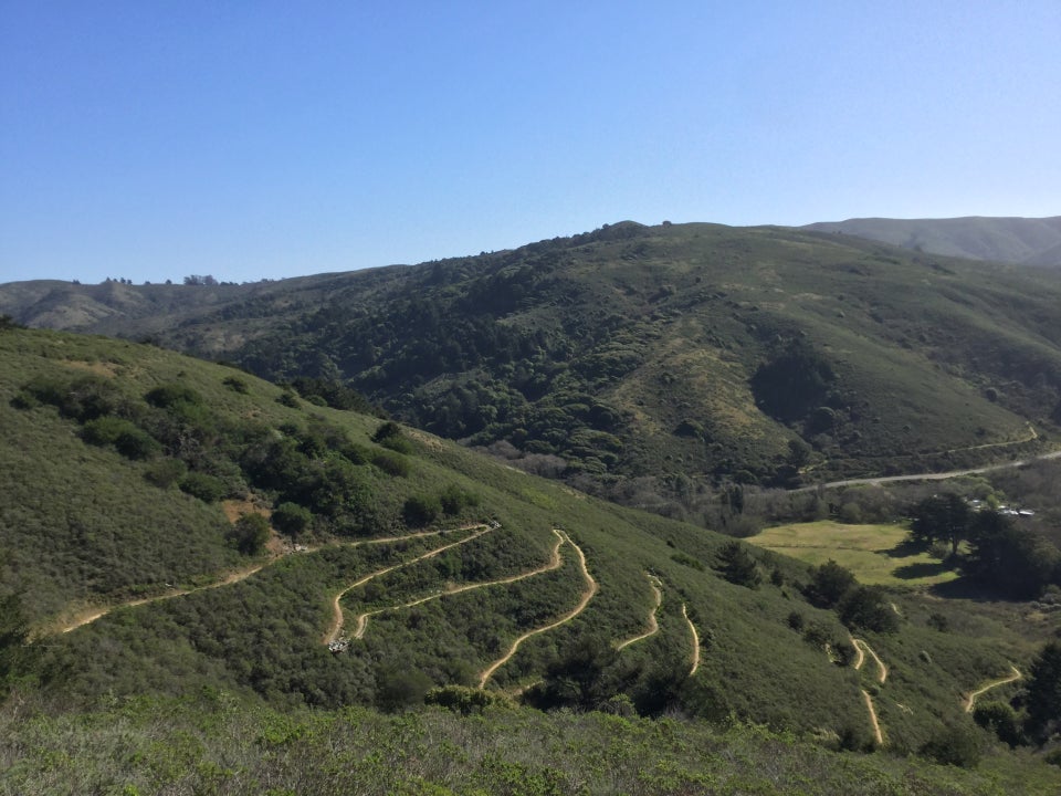 Clear blue sky above Marin hills, the nearby hill with a series of clear switchbacks cut into it.