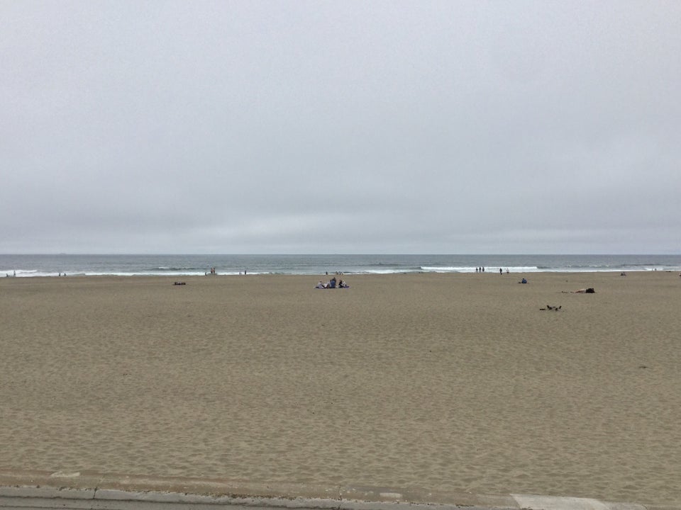 Ocean beach and the Pacific Ocean under an overcast sky.