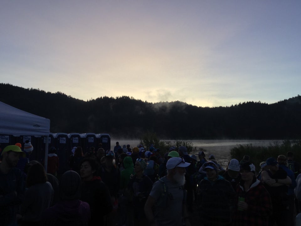 Spooner lake before dawn, the sky brightening above dark hills, mist over the lake, TRT racers in the foreground