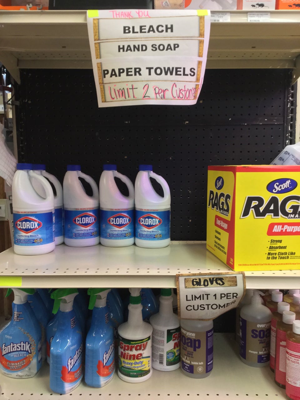 Shelves with Clorox bleach, Scott rags, under a sign stating limit 2 per customer, gloves limit 1 per customer, other cleaning supplies below.