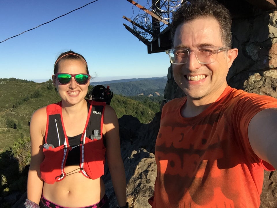 Sunlit Krissi and Tantek at Mount Tam’s East Peak with the West Peak and hills behind them