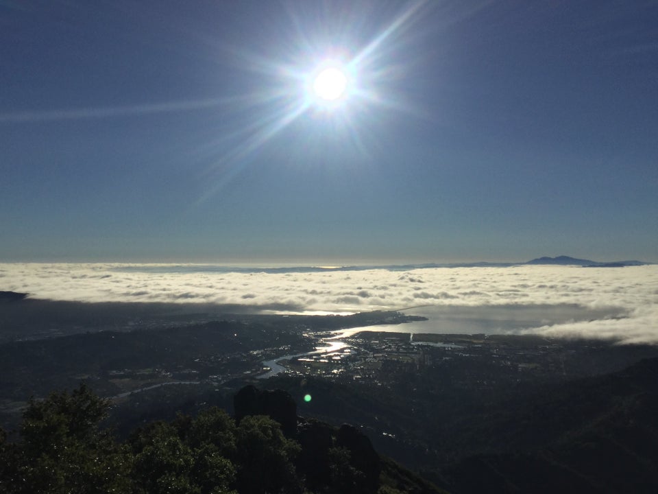 Facing East from Mount Tam, with the sun rising over a cloud cover, the bay, and hills in the foreground