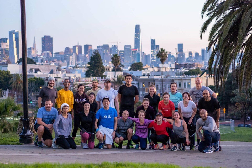 November Project San Francisco group photo in Dolores Park with a view of early morning San Franciso in the background.