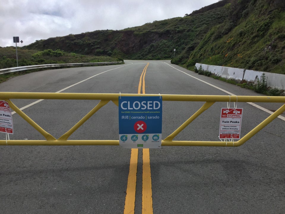 Yellow barricade across the North entrance to Twin Peaks, with a large sign posted in the middle of it saying CLOSED with additional details.