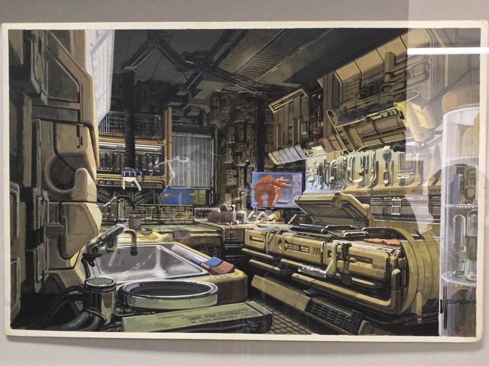 Photorealistic painting of the inside of a future urban kitchen, with highly stylized spaceship-style cabinets above, counters around the edge of the room, a window, an entertainment display, a sink, press oven, various utensils hanging from the wall.