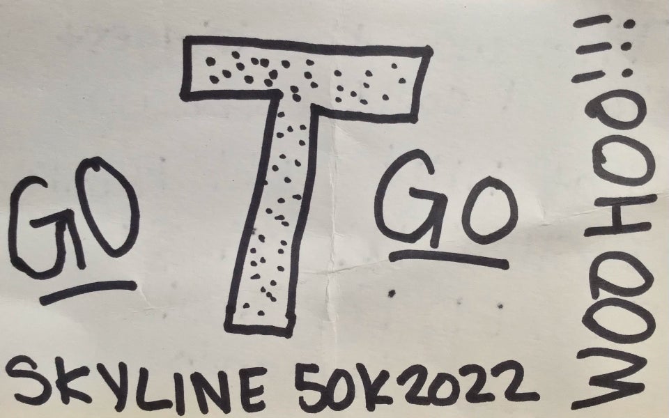 Plain white index card with “GO T GO, SKYLINE 50K 2022, WOO HOO !!!” written on it in black marker.