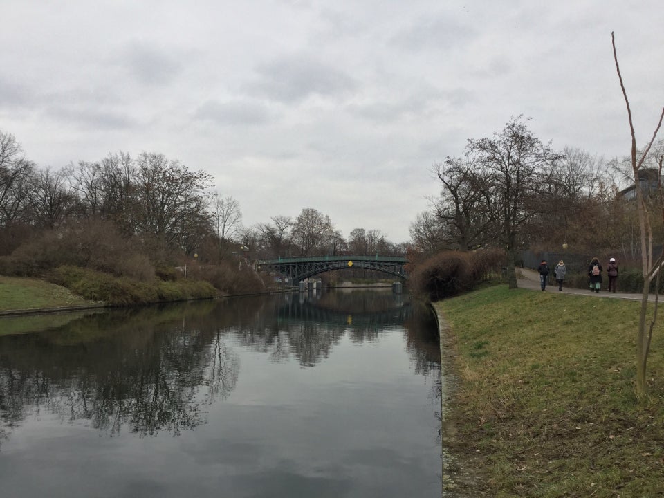 Overcast sky, green bridge over a canal, with rising berms on either side.