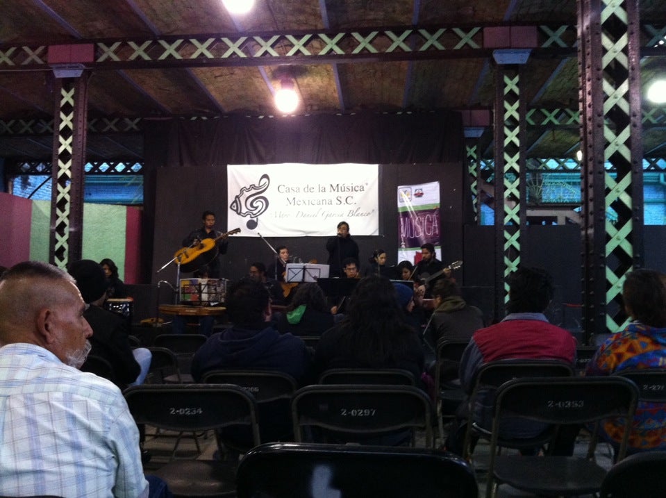 Presentación de evento en la Casa de Música, en el que está tocando un grupo en la tarima y público observando. 